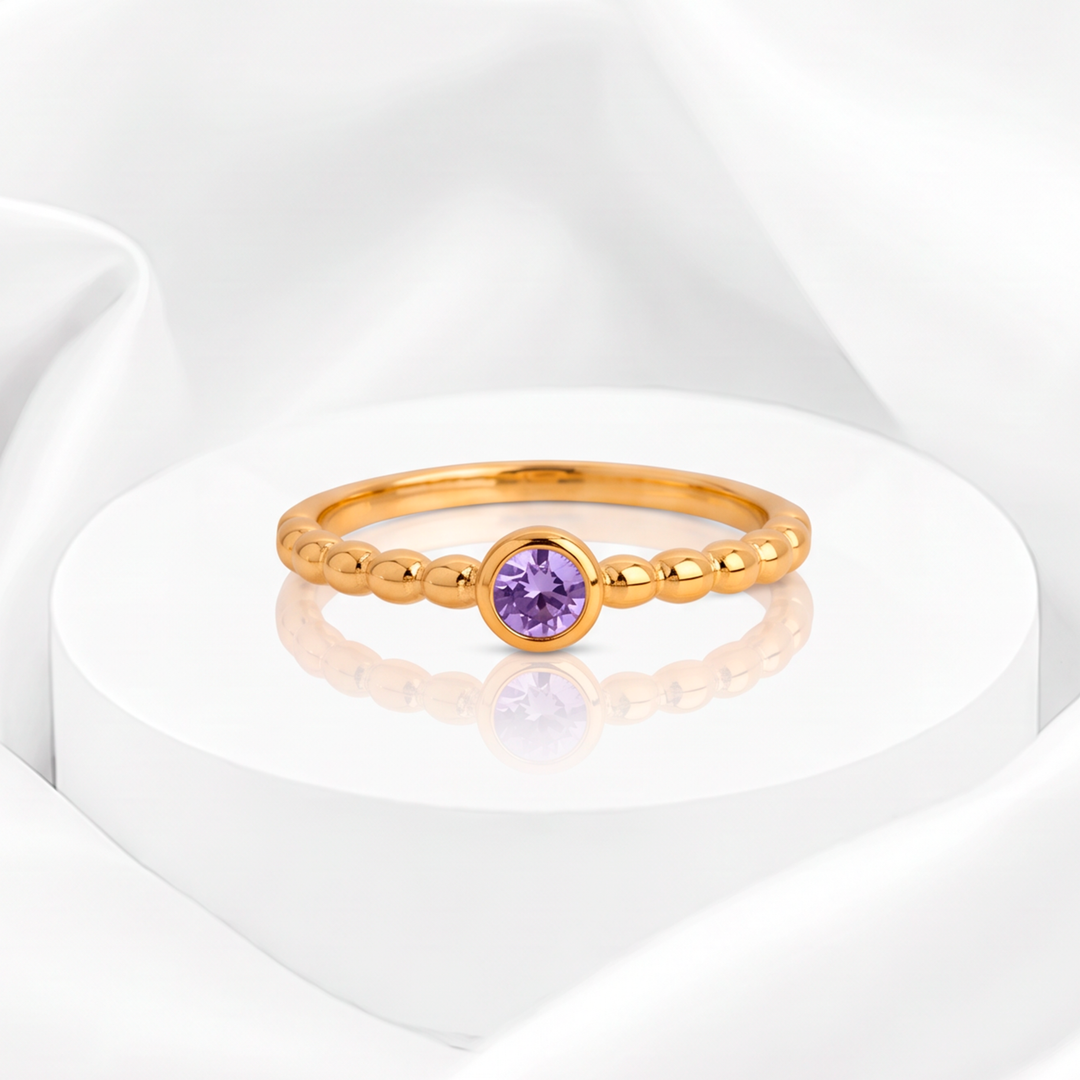 Anillo fino para mujer marca Belle en acero bañado en oro de 18k estilo esferas con circonia redonda lila en engaste biselado.
