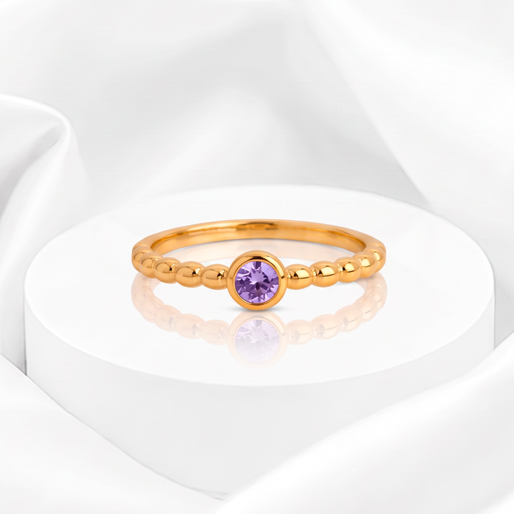 Anillo fino para mujer marca Belle en acero bañado en oro de 18k estilo esferas con circonia redonda lila en engaste biselado.
