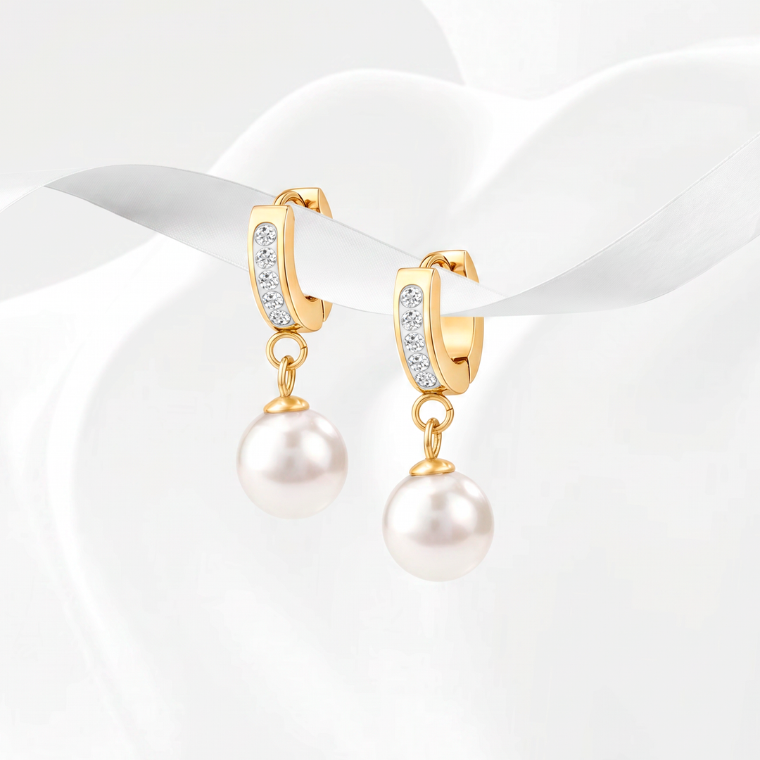 Aretes de argolla estilo huggie para mujer en acero quirúrgico 316 con baño de oro de 18k, decorados con cristales blancos pavé y un dije removible de perla blanca en forma de gota.