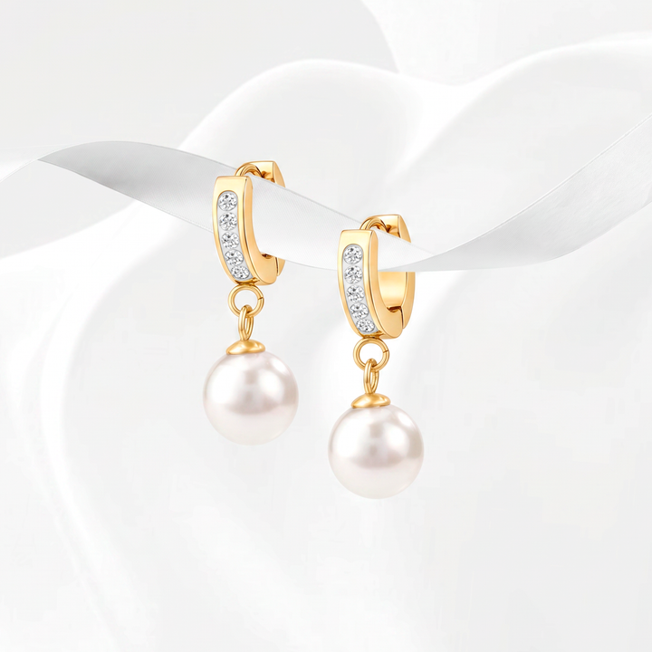 Aretes de argolla estilo huggie para mujer en acero quirúrgico 316 con baño de oro de 18k, decorados con cristales blancos pavé y un dije removible de perla blanca en forma de gota.