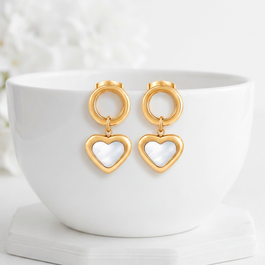 Aretes colgantes para mujer de acero quirúrgico 316 con baño de oro de 18k, con un dije circular texturizado y un corazón central de nácar blanco natural.