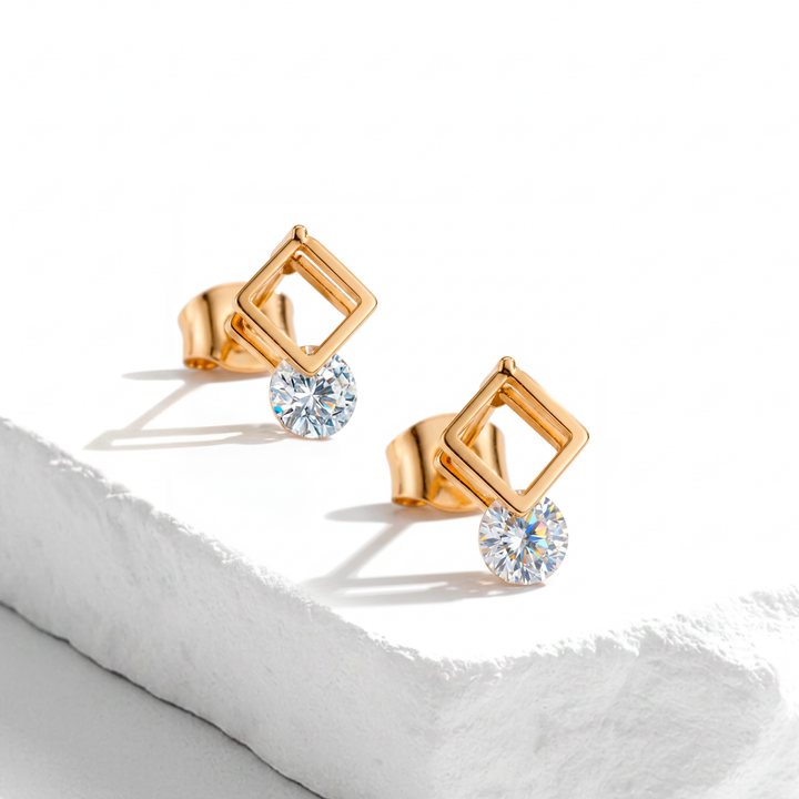 Aretes de botón para muje en acero inoxidable dorado, con diseño de marco cuadrado calado y un cristal redondo blanco facetado colgante.