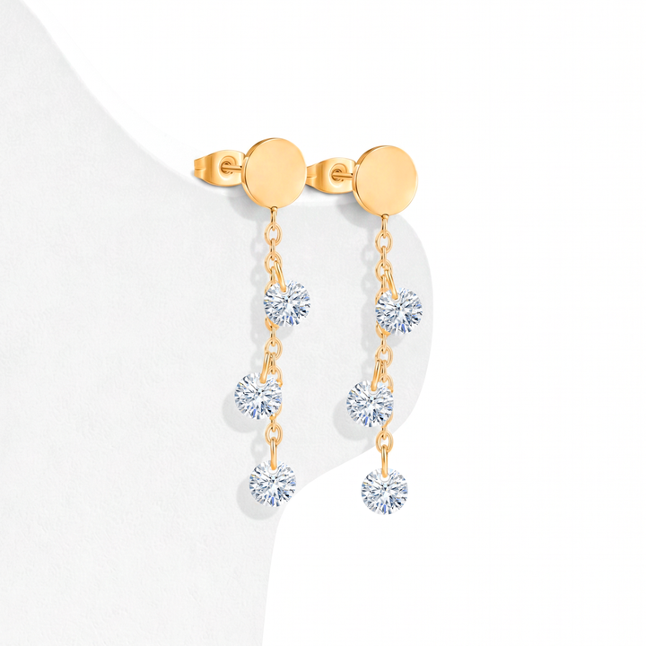 Aretes largos colgantes para mujer de acero quirúrgico 316 con baño de oro de 18k, con diseño articulado de tiras en cascada y terminales de cristales blancos.