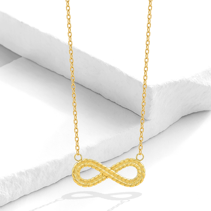 Collar dorado para mujer de acero quirúrgico 316 con baño de oro de 18k, que presenta una cadena fina y un dije central del símbolo del infinito con acabado dual liso y labrado.