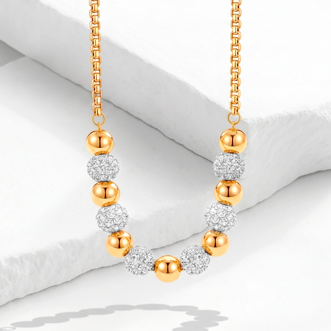 Collar de mujer con cadena veneciana de acero quirúrgico 316 y baño de oro de 18k, con un diseño curvado frontal de esferas doradas pulidas y cuentas de cristales blancos pavé.