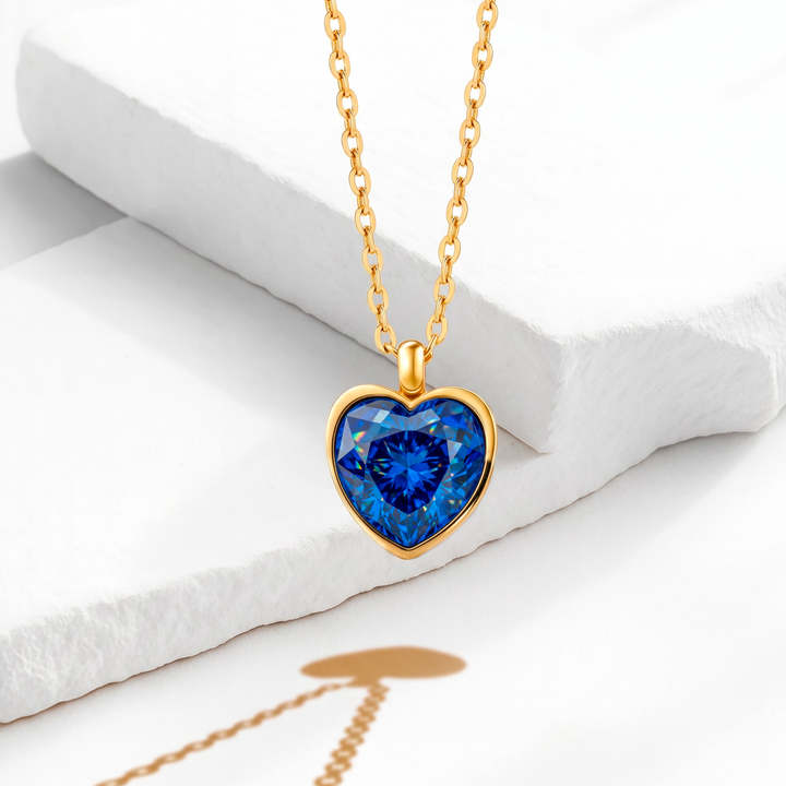 Collar para mujer con cadena fina de acero inoxidable con baño de oro de 18k y dije colgante de corazón facetado en cristal de color azul zafiro.