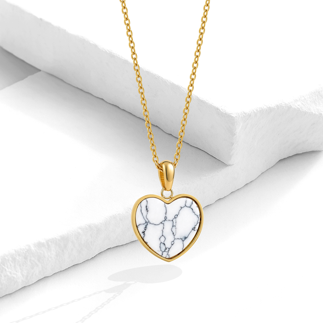 Collar dorado para mujer en acero quirúrgico 316 con baño de oro de 18k, con una cadena fina y un dije grande de corazón con textura marmoleada blanca y azul.