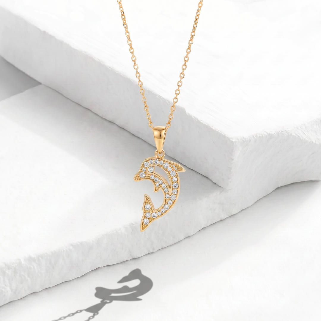 Collar para mujer marca Bodo con cadena fina de acero inoxidable bañado en oro de 18k y dije colgante de delfín saltando con cristales blancos circulares.