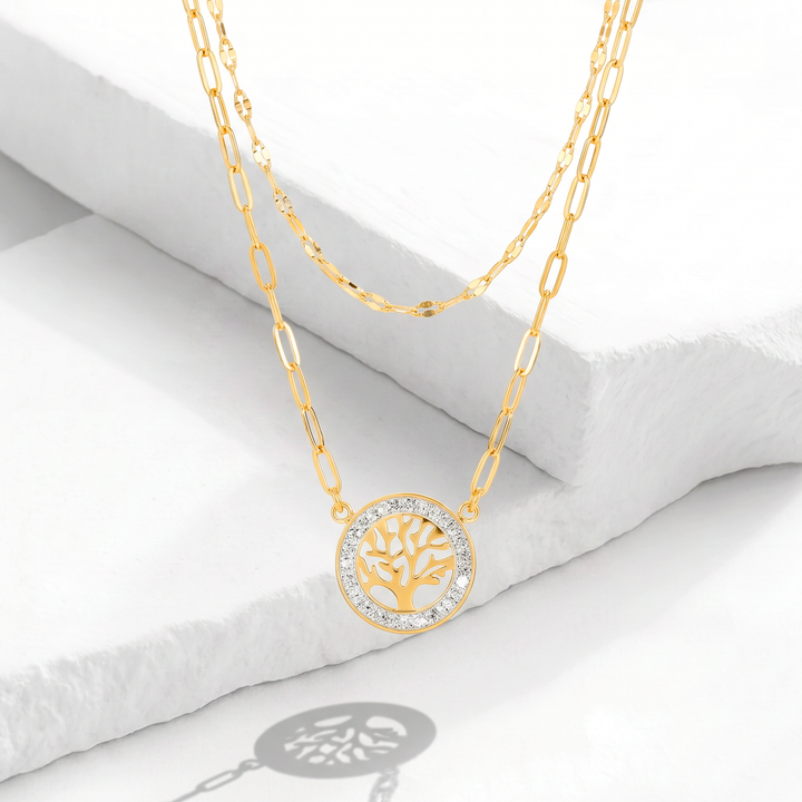 Collar de doble cadena para mujer marca Bodo en acero inoxidable bañado en oro de 18k con dije circular calado del Árbol de la Vida y contorno de cristales blancos.