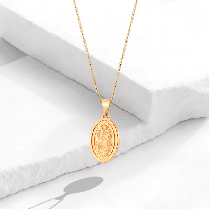 Collar dorado para mujer de acero quirúrgico 316 con baño de oro de 18k, que muestra una cadena fina y un dije de medalla ovalada de la Virgen de Guadalupe en relieve.
