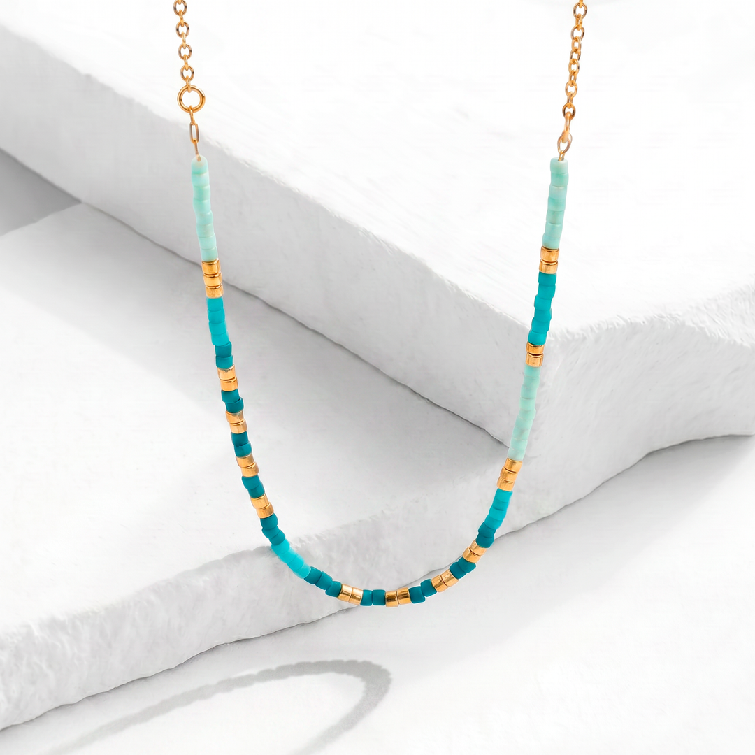 Collar corto para mujer marca Bodo con mostacillas cilíndricas en color celeste, turquesa y verde, con cadena y separadores de acero inoxidable bañado en oro de 18k.