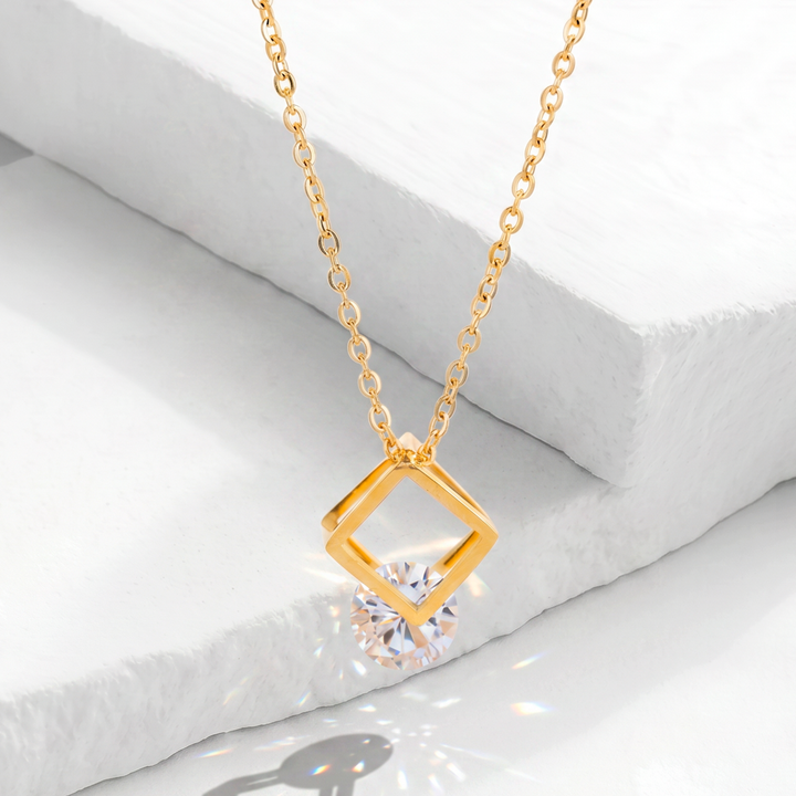 Collar para mujer con cadena fina de acero inoxidable dorado y dije tridimensional de marco cuadrado calado con un cristal redondo blanco facetado flotante.