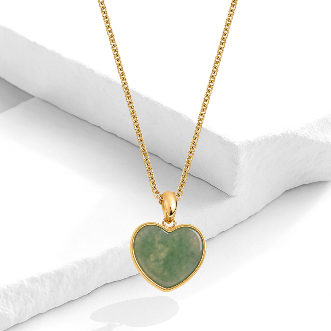 Collar dorado de mujer en acero quirúrgico 316L baño oro 18k con dije de corazón de piedra aventurina verde sobre fondo blanco texturizado.
