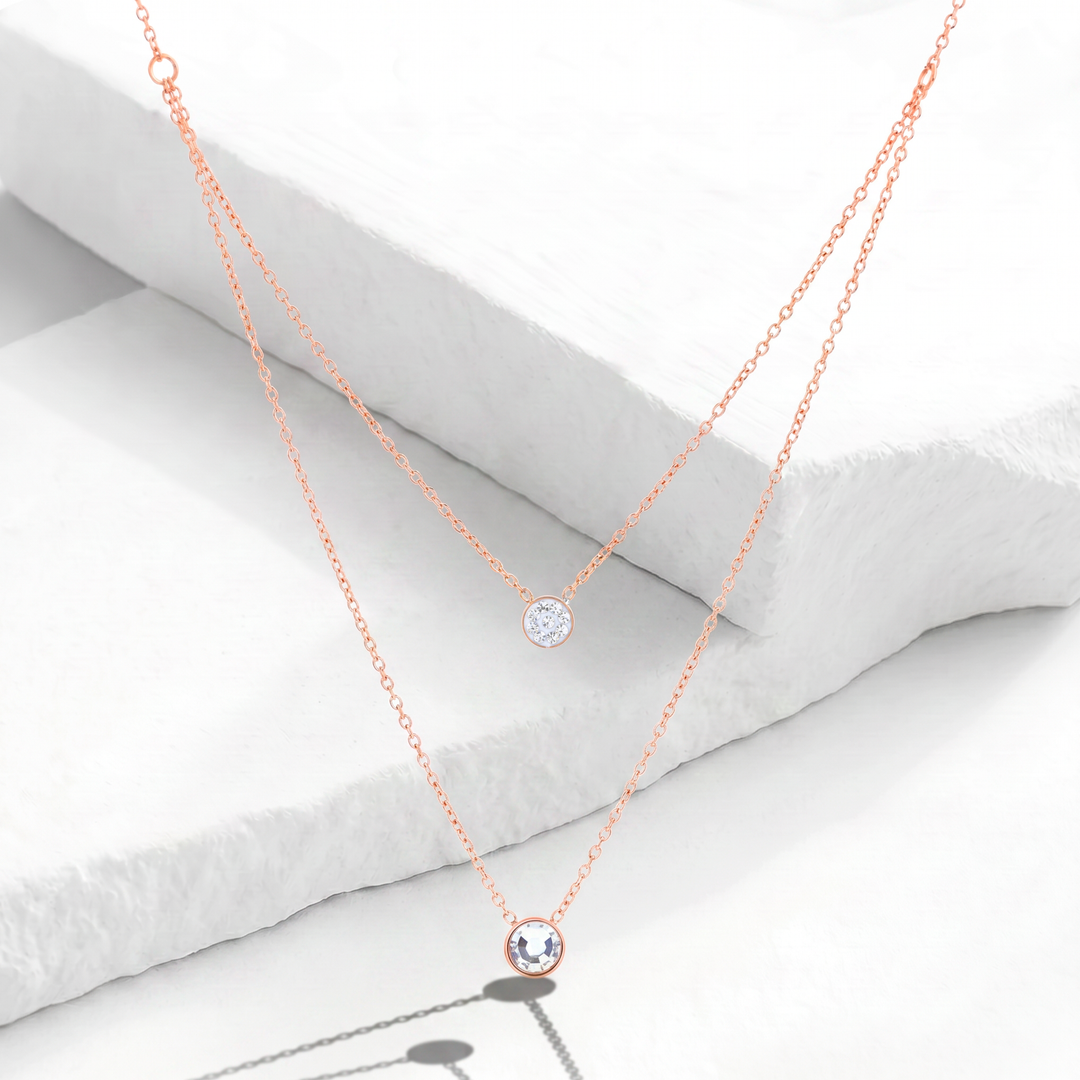Collar de doble capa para mujer marca Bodo en acero inoxidable bañado en oro rosa con dos dijes circulares punto de luz de cristales blancos.