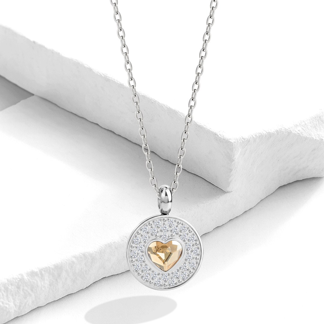 Collar plateado para mujer de acero quirúrgico 316 con una cadena fina y un dije circular doble que incluye un halo de cristales blancos y un corazón central de cristal color champaña.