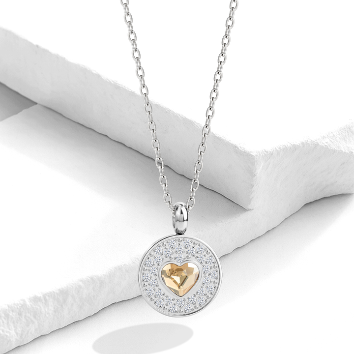 Collar plateado para mujer de acero quirúrgico 316 con una cadena fina y un dije circular doble que incluye un halo de cristales blancos y un corazón central de cristal color champaña.