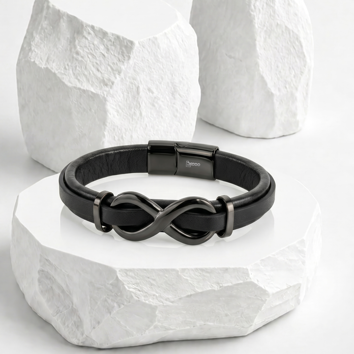Pulsera para hombre de biocuero negro con un dije central del símbolo del infinito y broche rectangular magnético en acero inoxidable pulido negro.