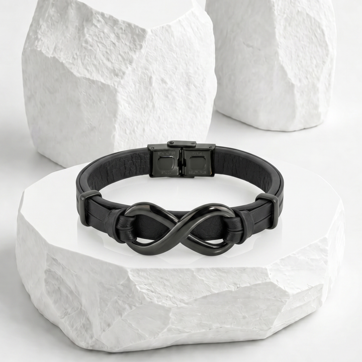 Pulsera para hombre de biocuero negro con diseño de doble banda paralela, equipada con un dije de infinito entrelazado y broche desplegable de acero inoxidable negro.