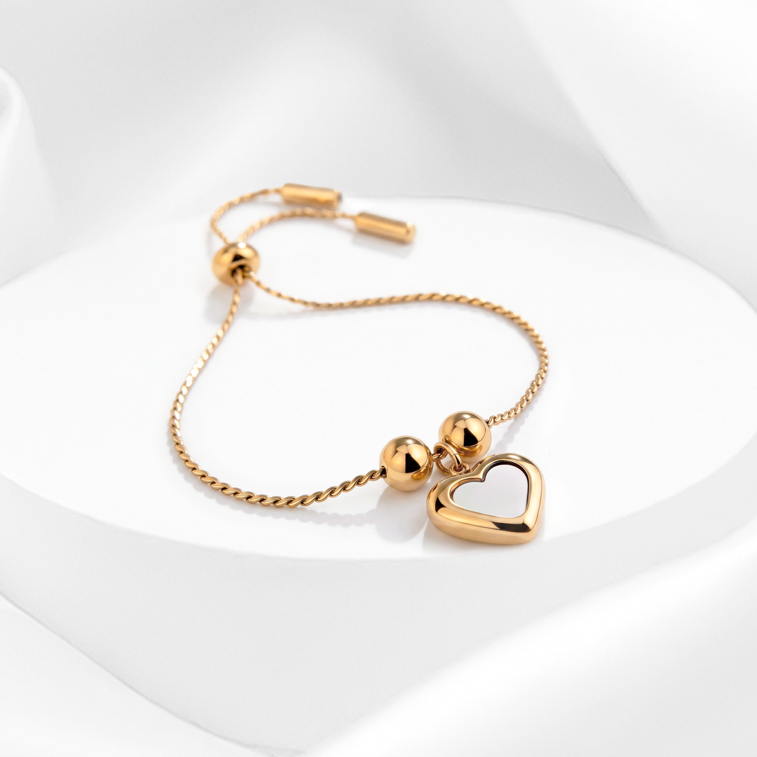 Pulsera ajustable de mujer en acero quirúrgico 316 con baño de oro de 18k, cadena fina trenzada con sistema slider y dije de corazón con nácar blanco central.