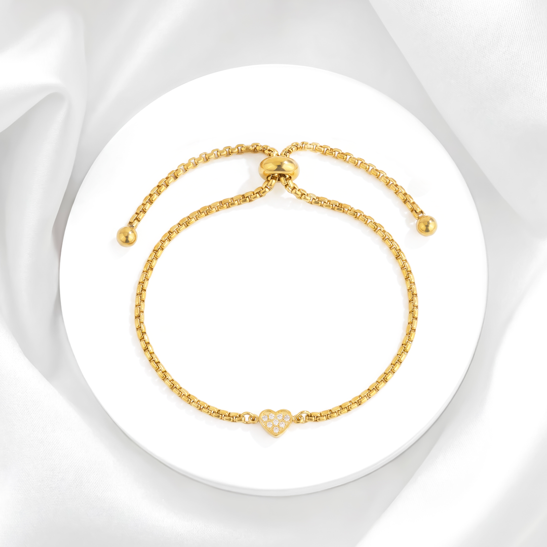 Pulsera ajustable para mujer de acero quirúrgico 316 con baño de oro de 18k, que presenta una cadena fina con cierre slider y un dije de corazón central con cristales blancos.