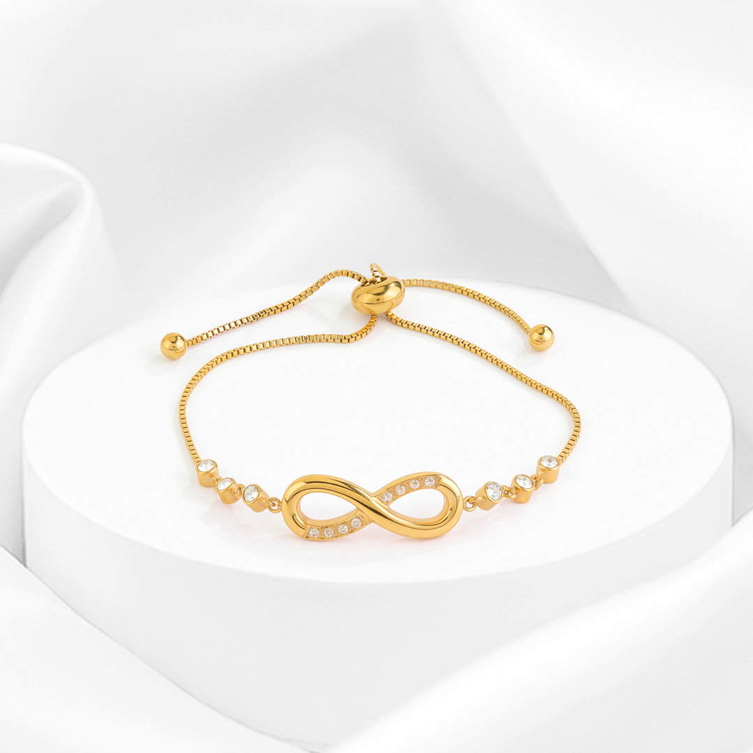 Pulsera ajustable para mujer confeccionada en acero quirúrgico 316 con baño de oro de 18k, con un dije del símbolo del infinito adornado con cristales blancos y cadena decorada con cristales circulares.