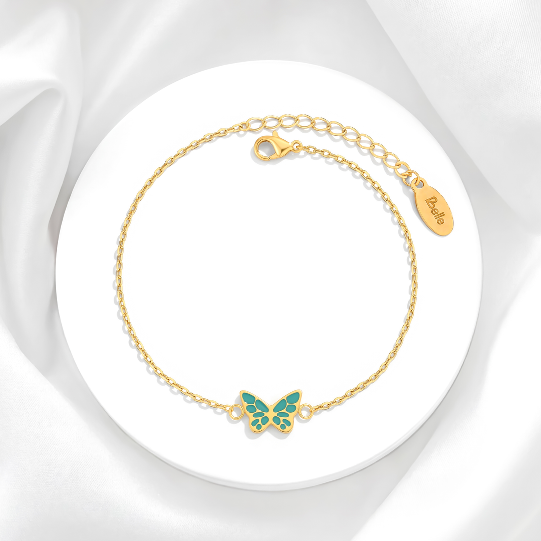 Pulsera para mujer marca Belle con cadena fina de eslabones de acero bañado en oro de 18k y dije de mariposa esmaltada en color turquesa verdoso.