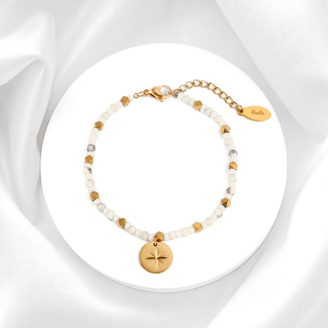 Pulsera para mujer marca Belle compuesta por esferas de acero bañado en oro de 18k con un dije de medalla circular que tiene una estrella grabada y una moisanita blanca central.