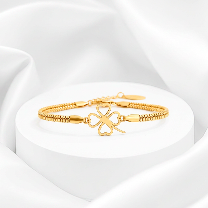 Pulsera de mujer con baño de oro de 18 quilates en acero quirúrgico 316, con doble cadena de eslabones cúbicos y un dije central de trébol calado con corazones huecos.