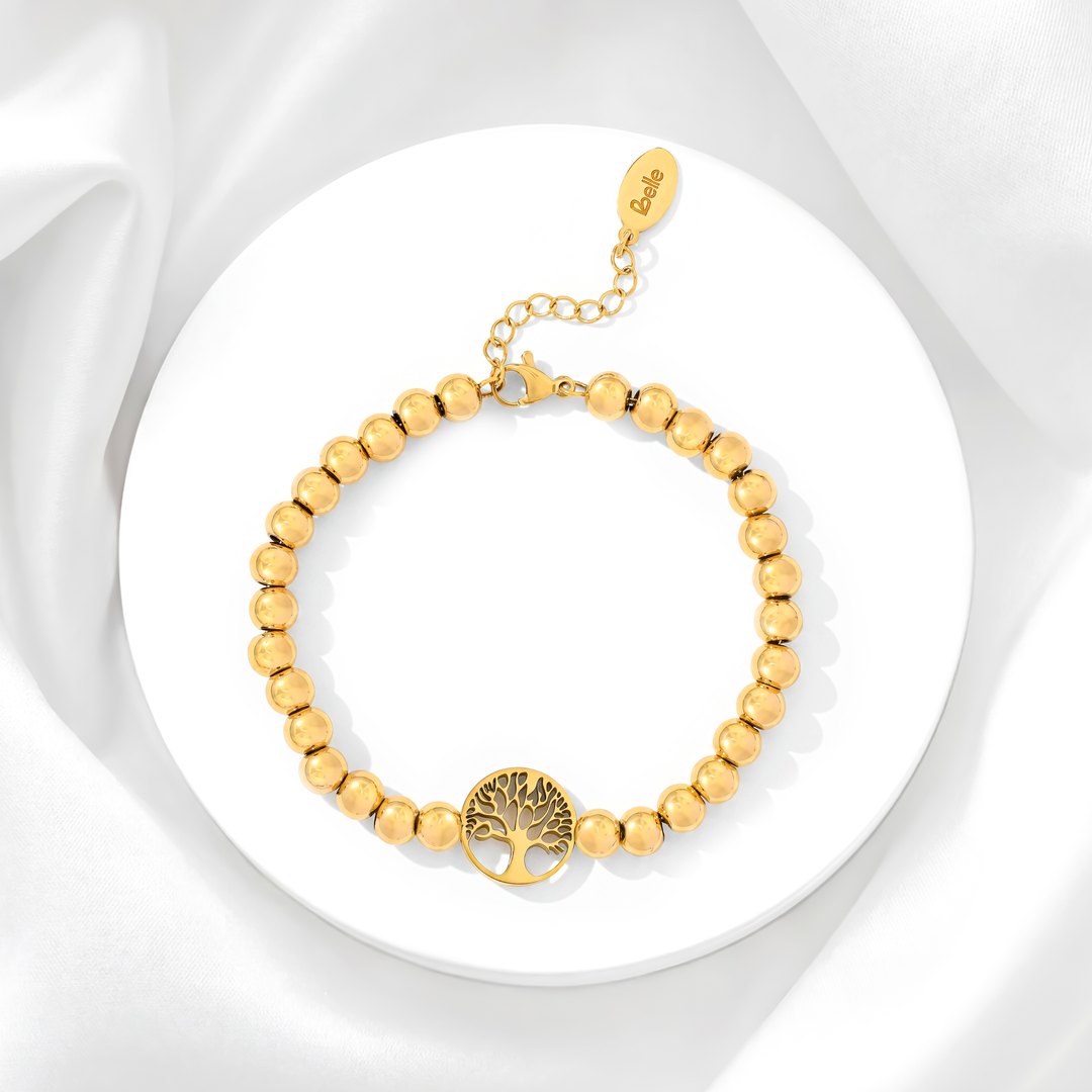 Pulsera de mujer de acero quirúrgico 316 con baño de oro de 18k, compuesta por una hilera de esferas doradas lisas pulidas y un dije circular calado del Árbol de la Vida.