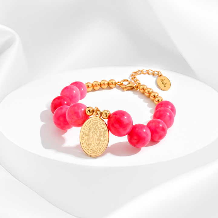 Pulsera de mujer de acero quirúrgico 316 con baño de oro de 18k, compuesta por cuentas esféricas de color rosa pastel y una medalla ovalada calada de la Virgen de Guadalupe.