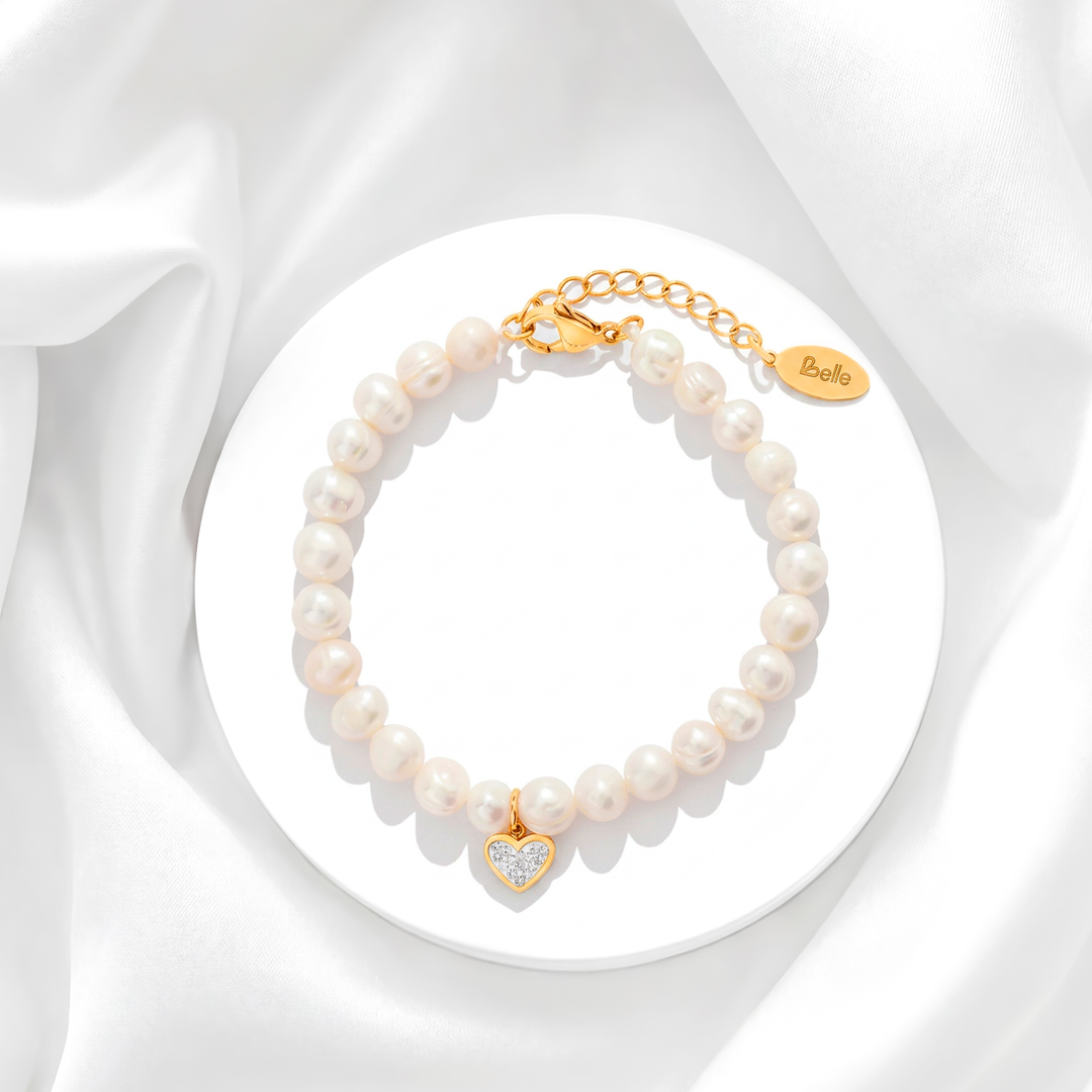 Pulsera de perlas de río naturales para mujer con broche de acero quirúrgico en baño de oro de 18k y un dije de corazón colgante con cristales blancos.