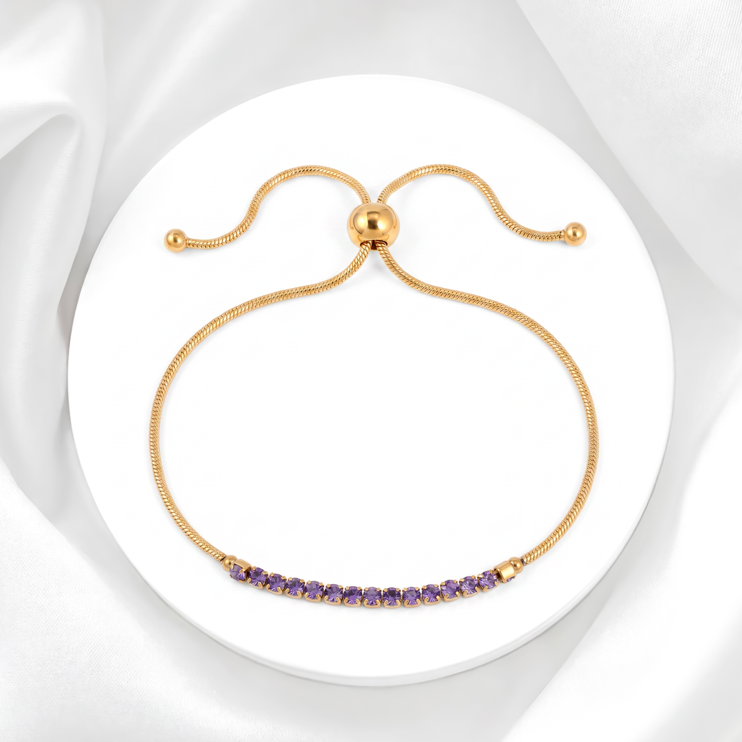 Pulsera ajustable para mujer marca Belle estilo tennis en acero bañado en oro de 18k con carril de cristales strass blancos y tres cristales centrales color lila.