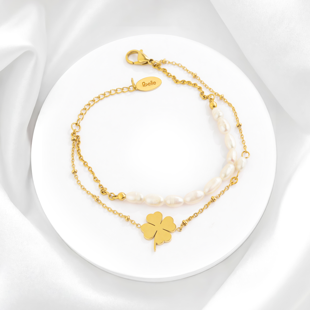 Pulsera de doble cadena para mujer en acero quirúrgico 316L con baño de oro de 18k, decorada con perlas de río naturales barrocas y un dije de trébol de cuatro hojas liso y pulido.