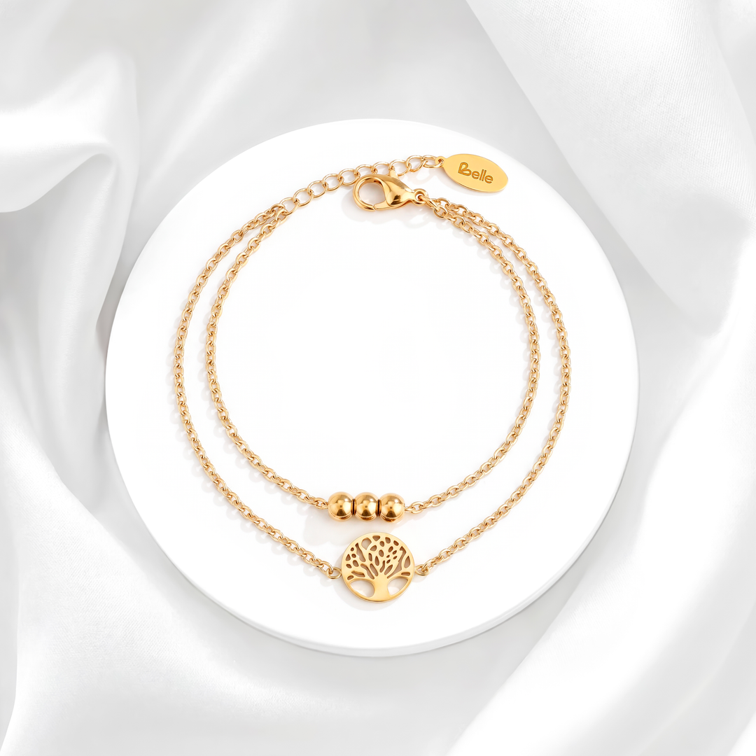 Pulsera de mujer con doble cadena en acero quirúrgico 316 con baño de oro de 18k, detallada con tres esferas doradas y un dije circular calado del Árbol de la Vida.