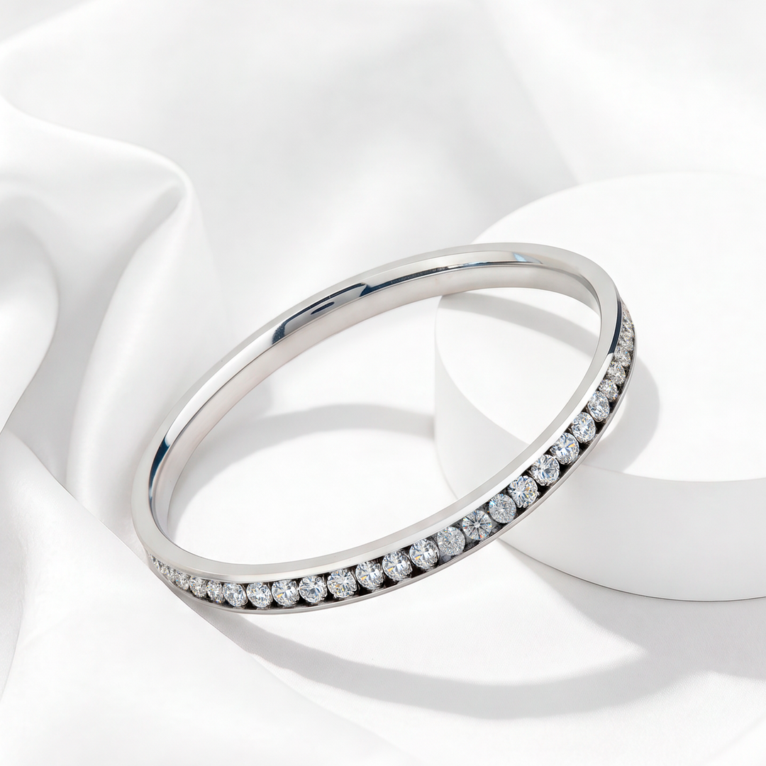 Brazalete rígido de mujer en acero 316L plateado con hilera densa de cristales blancos pavé sobre fondo blanco.