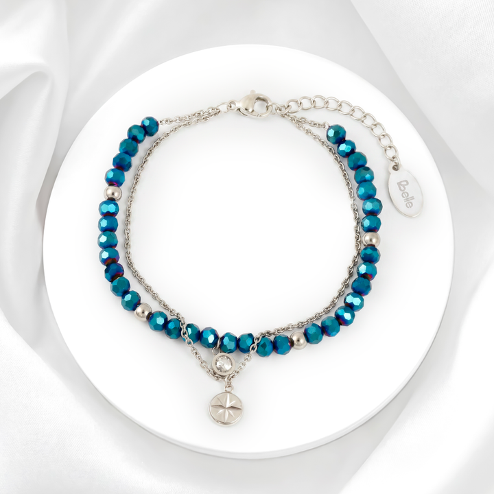 Pulsera doble capa para mujer marca Belle en acero inoxidable plateado con dije de medalla circular de estrella y un dije con cristal moisanita azul profundo.