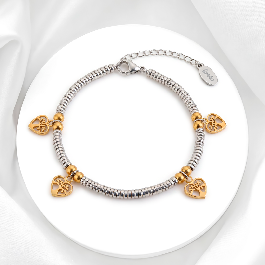 Pulsera bicolor de mujer en acero 316L plateado con dijes de corazón en baño de oro 18k sobre soporte blanco circular.