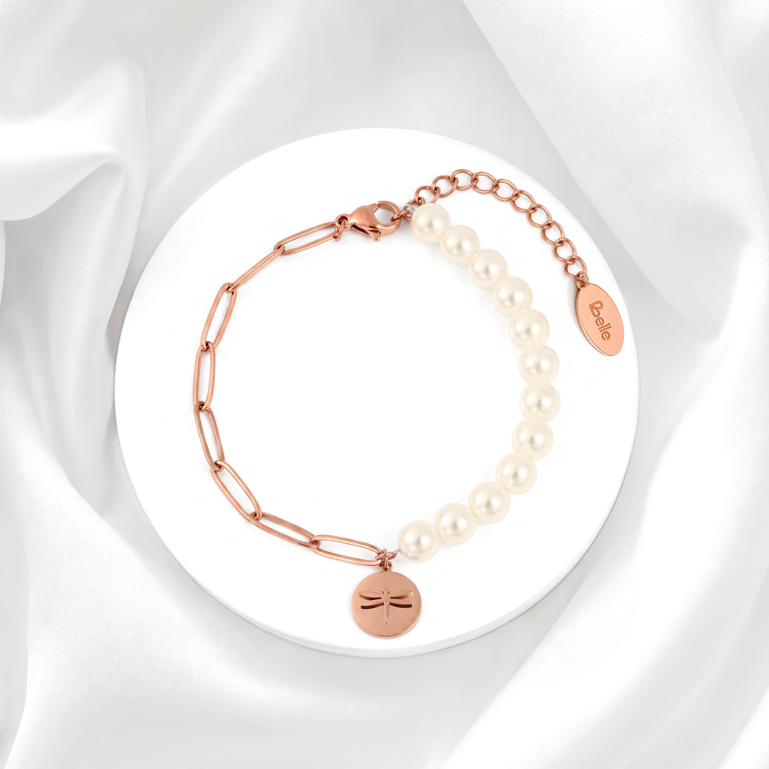 Pulsera para mujer marca Belle con cadena fina de acero bañado en oro rosa de 18k, tres perlas blancas cultivadas y un dije colgante de medalla circular con grabado de libélula.
