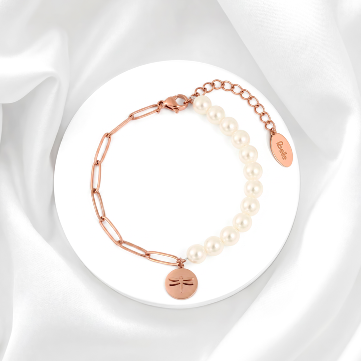 Pulsera para mujer marca Belle con cadena fina de acero bañado en oro rosa de 18k, tres perlas blancas cultivadas y un dije colgante de medalla circular con grabado de libélula.